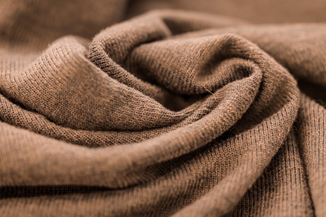 Detailed close-up of a warm brown wool fabric showcasing its soft texture and fine knitting.