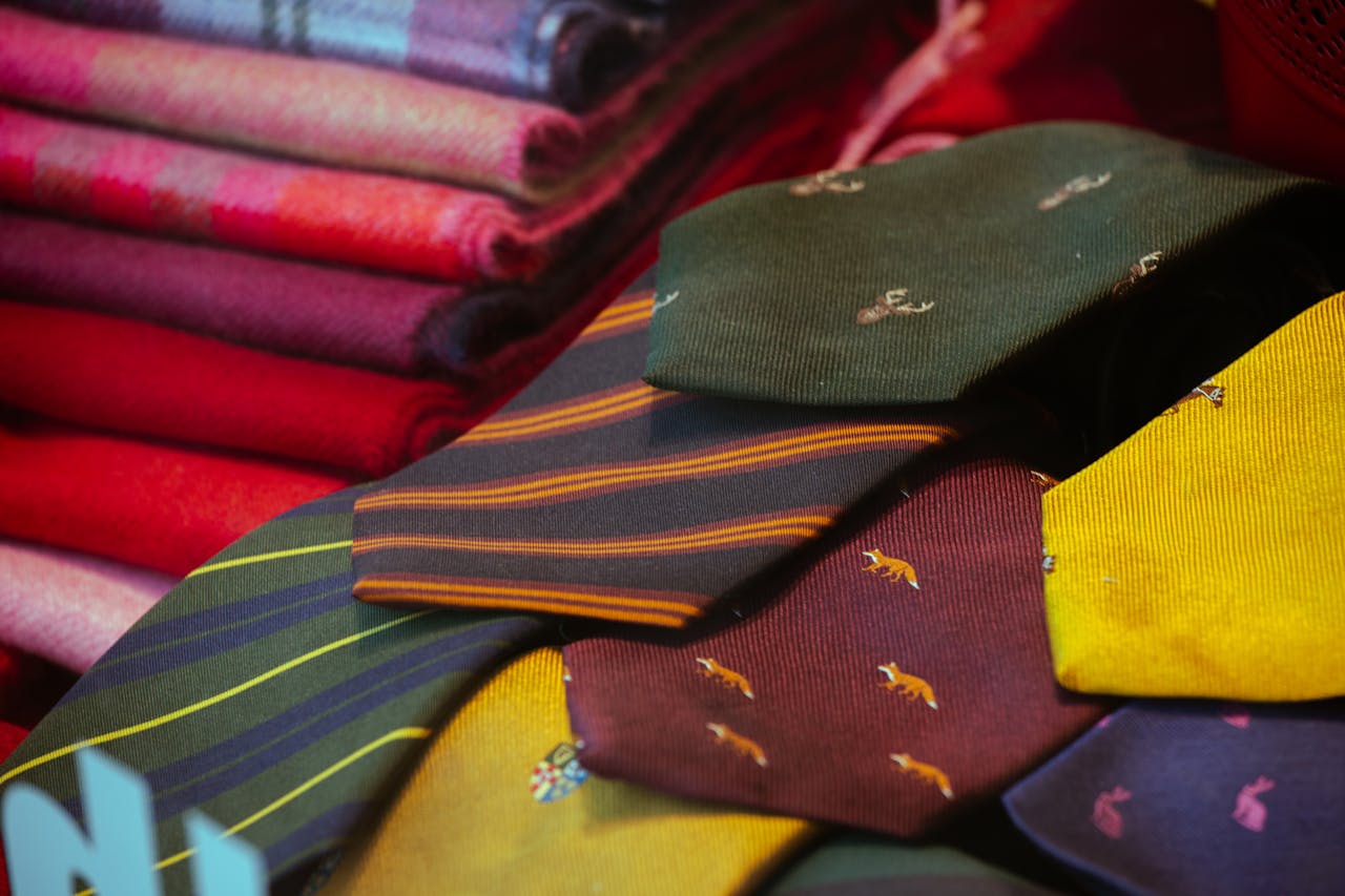 A vibrant display of patterned silk ties and colorful wool fabrics, perfect for men's fashion and textile lovers.